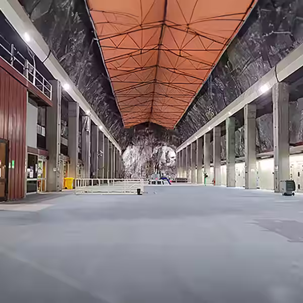 Revestimiento técnico continuo sobre un piso industrial de hormigón con demarcación de seguridad amarilla para pasillo de tránsito intensivo.